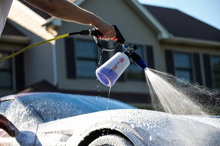Foam cannon laying snow foam over a car mid-wash